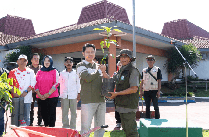 Ketua BASKOSMAS,Cak Ndan (kanan) saat terima bibit pohon dilokasi.